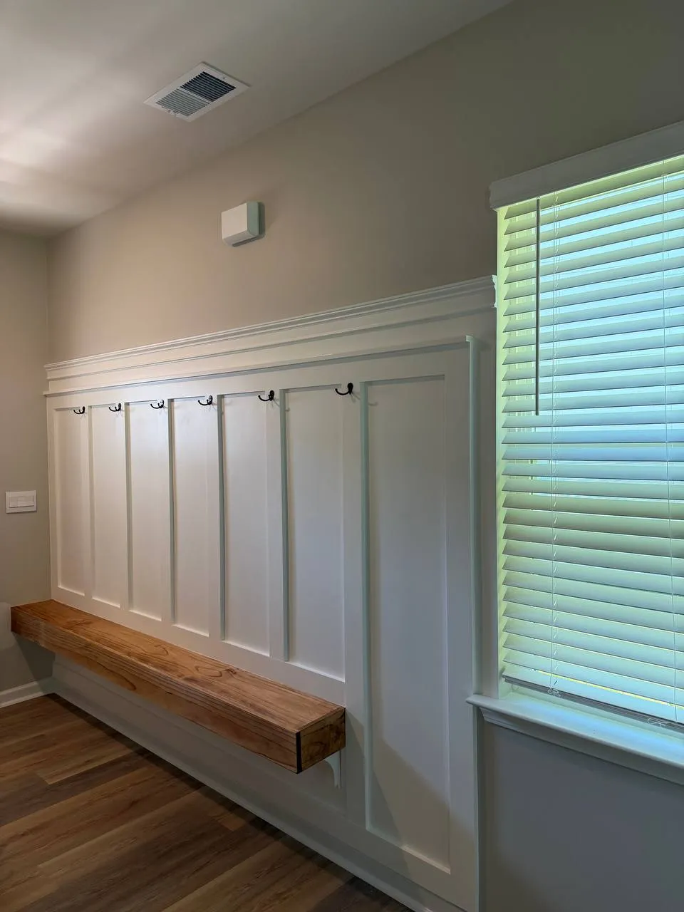 Entryway board and batten wall with coat hooks and a floating wood bench